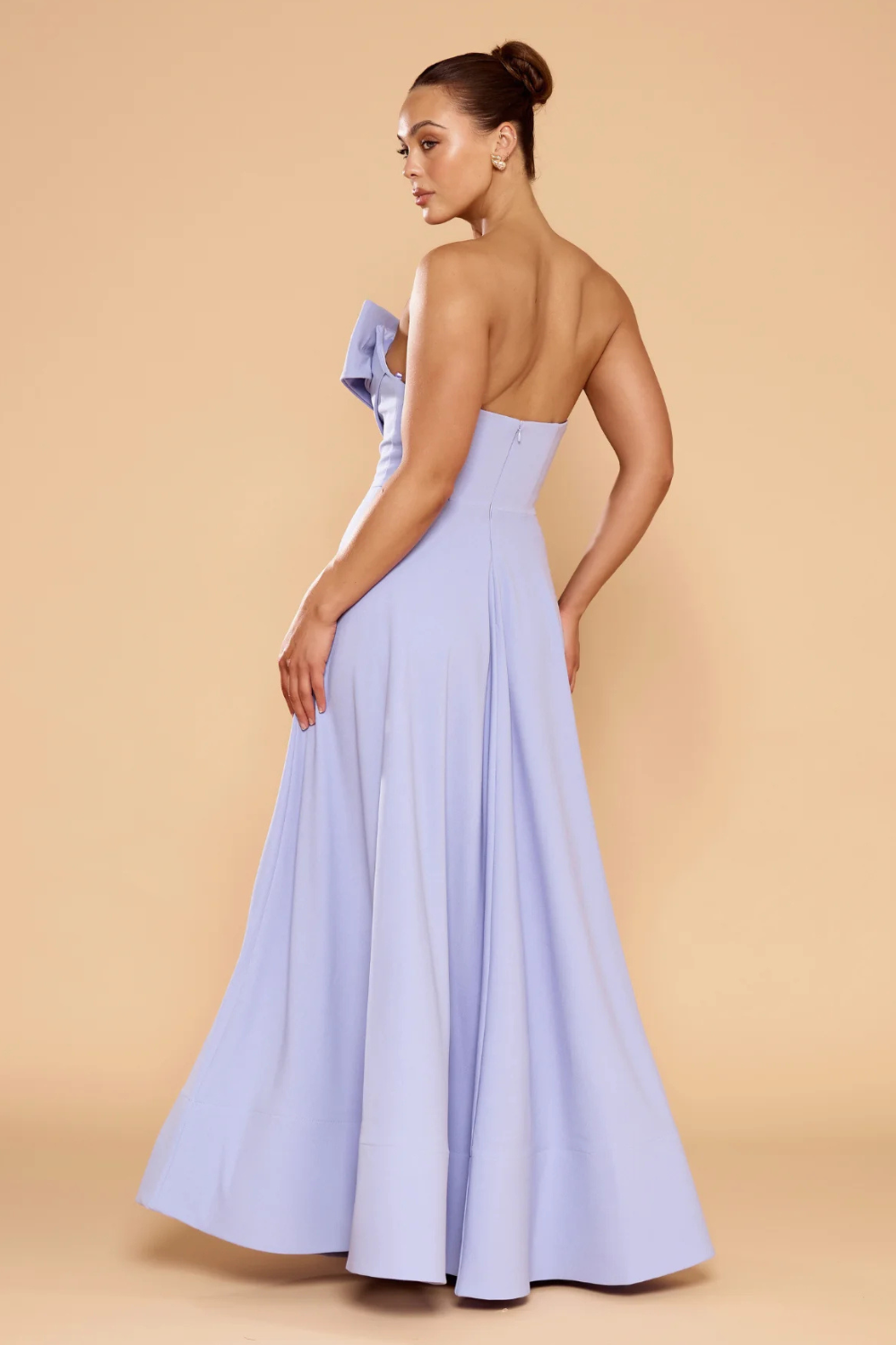 model wearing a light purple strapless gown, showcasing a low-cut open back and a flowing, floor-length A-line skirt