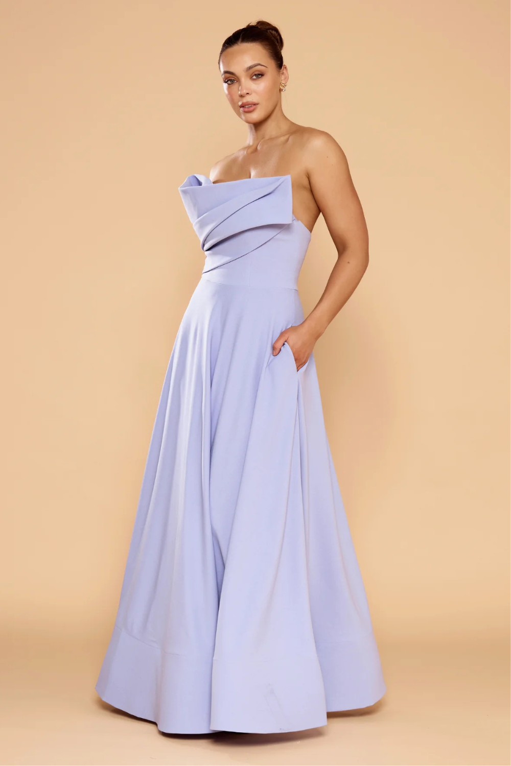 Woman wearing a strapless light blue gown against a beige background