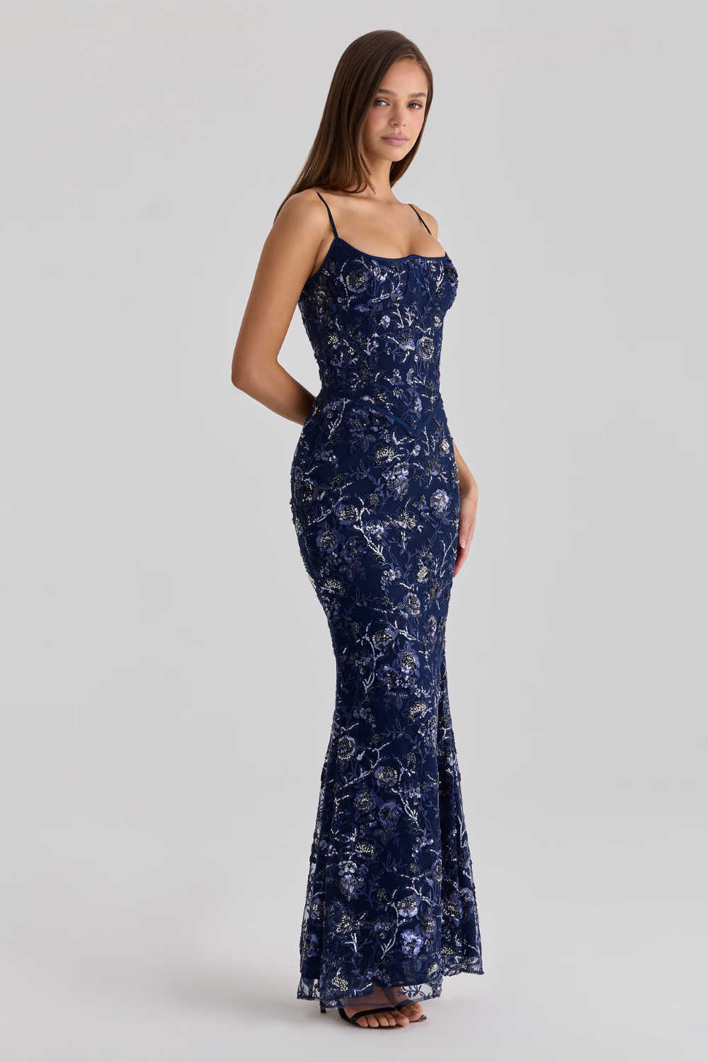 Woman wearing a navy floral evening gown on a light gray background