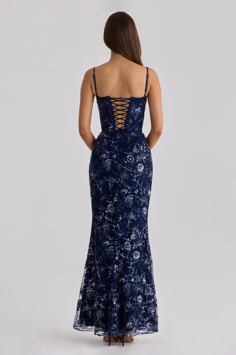 Woman wearing a navy blue floral dress with lace-up back on a white background