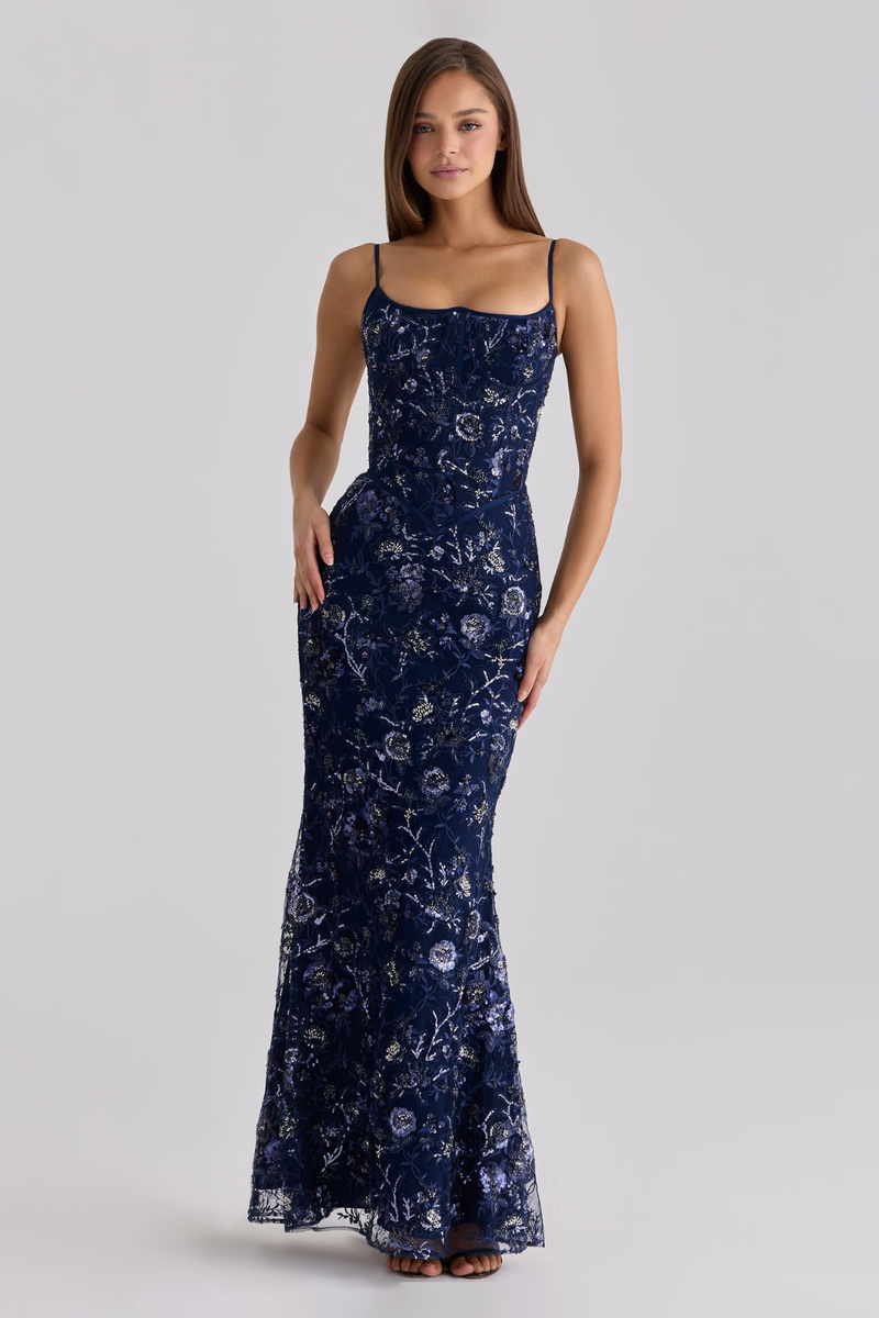Woman wearing a navy blue floral dress on a light gray background