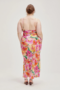 back side profile of a model wearing a vibrant floral print bias cut silk slip dress.