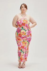 A model wearing a vibrant floral print bias cut silk slip dress.